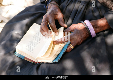 Femme âgée de tourner les pages d'un livre de cantiques, Sehitwa, Botswana, Africa Banque D'Images