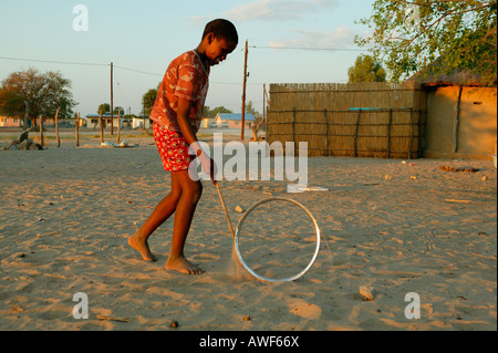 Garçon jouant avec jante sur la rue, Sehitwa, Botswana, Africa Banque D'Images