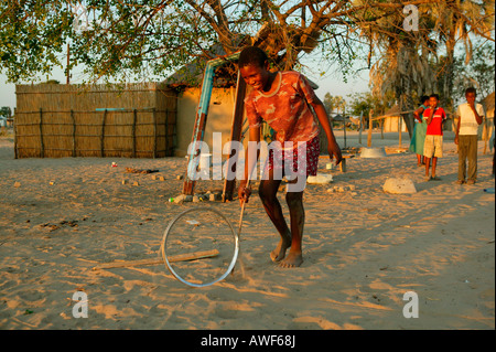 Garçon jouant avec jante sur la rue, Sehitwa, Botswana, Africa Banque D'Images