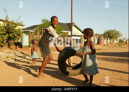 Garçon jouant sur chemin de terre avec un vieux pneu, Sehitwa, Botswana, Africa Banque D'Images