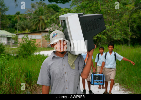 Homme portant un téléviseur à sa maison, les Arawak, Santa Mission, Guyana, en Amérique du Sud Banque D'Images