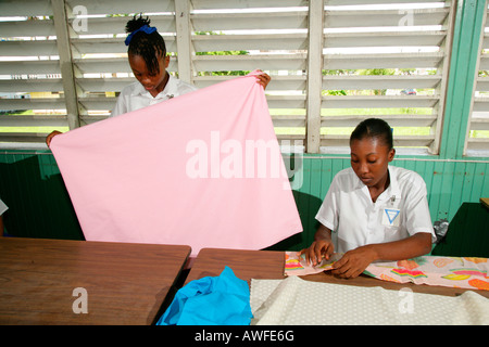Les jeunes filles portant des uniformes scolaires dans la classe de couture dans un centre de formation pour les jeunes femmes à New Amsterdam, au Guyana, en Amérique du Sud Banque D'Images