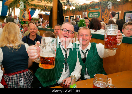 Des hommes habillés en costume national holding up leurs verres à une fête folklorique dans Muehldorf am Inn, Upper Bavaria, Bavaria, Germ Banque D'Images