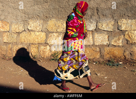 Une femme en vêtements traditionnels colorés passe devant un mur à Harar, Ethiopie, Afrique Banque D'Images