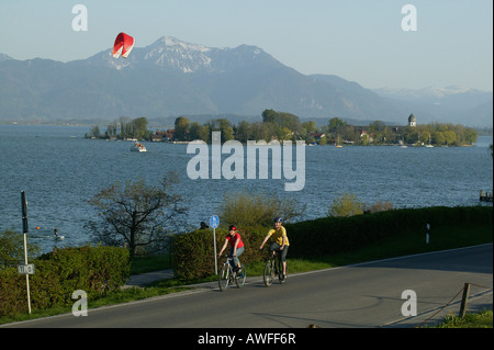 Les cyclistes le long du lac de Chiemsee et les frais généraux, un parapente Fraueninsel (Women's Island) dans l'arrière-plan, la Haute-Bavière, Bava Banque D'Images