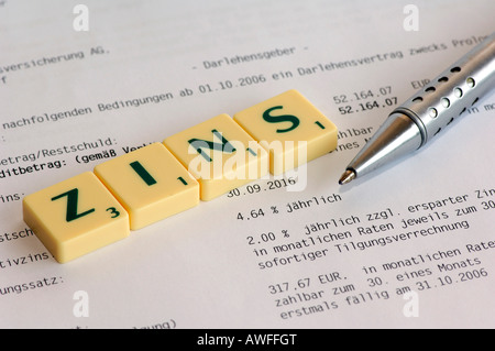 Photo symbolique, l'intérêt, une recharge bille allongé sur un contrat, scrabble Banque D'Images