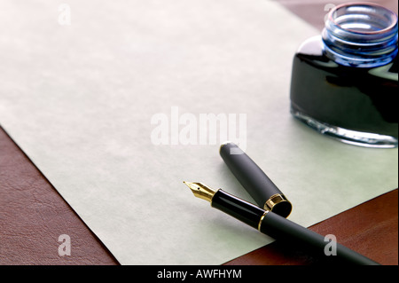 Stylo plume or nibbed filigranés papier coûteux et d'un encrier sur un bureau en cuir haut Banque D'Images