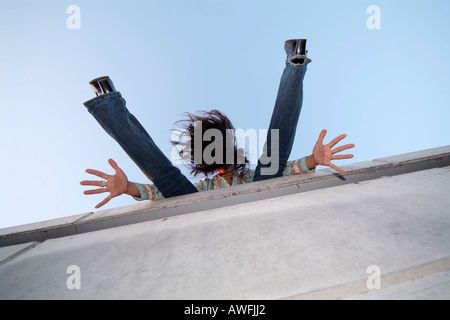 Crazy girl sur un mur s'étendant ses bras et jambes Banque D'Images