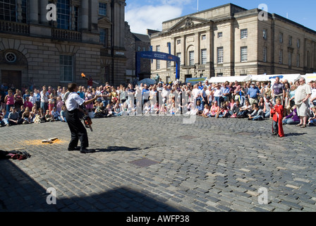 Dh Edinburgh Fringe Festival ROYAL MILE EDINBURGH Street artiste jonglant avec le feu jeune garçon helper Banque D'Images