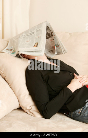 Femme d'âge moyen avec du papier journal sur son visage Banque D'Images