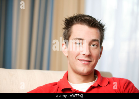 Jeune homme assis sur un canapé, portrait Banque D'Images