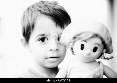 Jeune garçon est titulaire d'un modèle de poupée High key parution en noir et blanc à contraste élevé pour l'impact considérable de l'image Banque D'Images