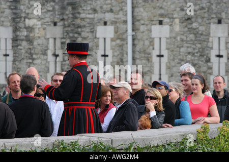 Un tour de Londres, le Beefeater parle à un groupe de touristes à visiter avant d'entrer dans la Tour de Londres Angleterre UK UE Banque D'Images