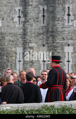 Un tour de Londres, le Beefeater parle à un groupe de touristes à visiter avant d'entrer dans la Tour de Londres Angleterre UK UE Banque D'Images