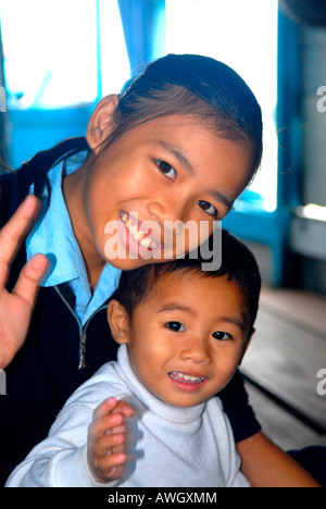 Asie Far East Vietnam Hue Perfume River, jolie jeune fille vietnamienne adolescente native souriante avec un bébé frère vague sur bateau dragon Banque D'Images