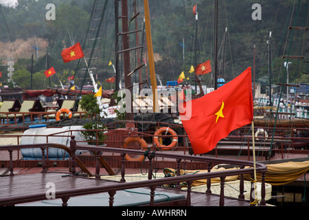 Drapeaux communiste soufflent dans le vent au sommet des voiliers de la baie de Halong VIETNAM Banque D'Images
