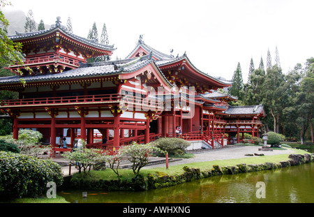 L'approche de Byodo-In Temple japonais sur l'Île Oahu, Hawaii, est au-dessus de l'élégant pont peint rouge traversant le lac Banque D'Images