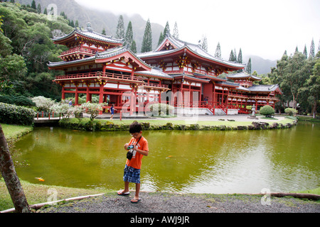 L'approche de Byodo-In Temple japonais sur l'Île Oahu, Hawaii, est au-dessus de l'élégant pont peint rouge traversant le lac Banque D'Images