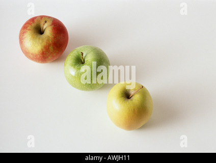 Trois pommes, rouge, vert, jaune, en diagonale, contre fond blanc Banque D'Images