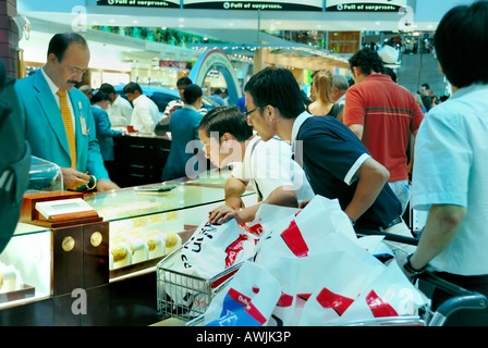 Dubaï, Émirats Arabes Unis Aéroport Shopping, à l'intérieur, la foule touristes chinois hommes amis, acheter des bijoux, point de vente aéroport hors taxes Banque D'Images