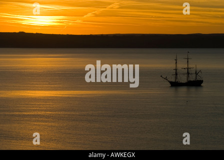 Un voilier gréé carré à St Austell Bay, avec le soleil se levant sur le pays Banque D'Images