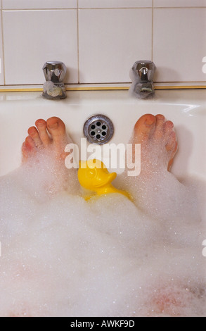 Homme avoir tremper dans un bain de mousse avec canard en plastique Banque D'Images