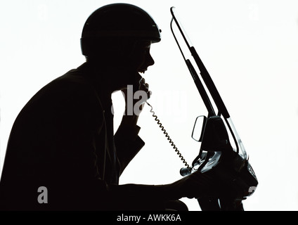 L'homme à l'aide de téléphone sur scooter, silhouette Banque D'Images