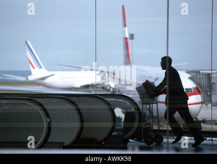 L'homme se hâtait avec chariot à bagages dans l'aéroport Banque D'Images