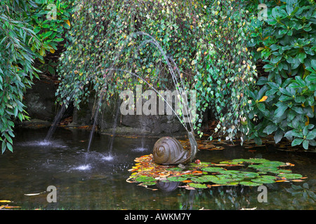 Une charmante fontaine en forme d'un escargot dans un petit étang Banque D'Images