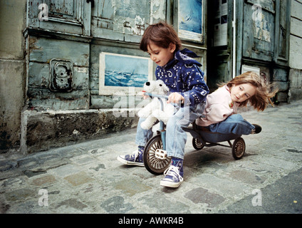 Little Boy riding tricycle à petite fille sur le dos Banque D'Images