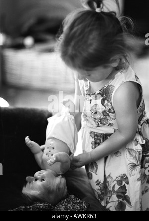 Girl holding baby doll, b&w Banque D'Images