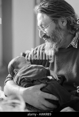 Mature man holding baby, side view, b&w Banque D'Images