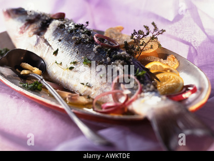 Poisson entier cuit avec les agrumes et les herbes sur lave, close-up Banque D'Images