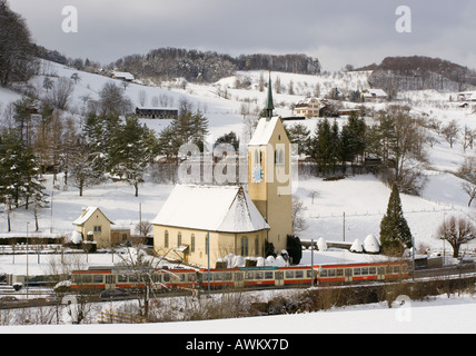 Le rouge et le train jaune sur la jauge la plus étroite voie de chemin de fer en Suisse en paysage de neige à Oberdorf Canton de Bâle dans village Banque D'Images