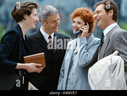 Quatre personnes debout à l'extérieur, smiling businesswoman on cell phone Banque D'Images