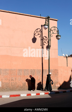 Homme et femme âgés marchant dans des directions opposées le long d'un trottoir dans le quartier historique de la Médina, Marrakech, Maroc, Afrique Banque D'Images