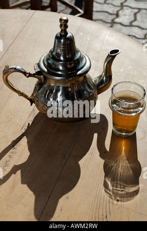 Théière marocaine ornée et le verre sur une table dans un café de la rue dans le quartier historique de Médina, Marrakech, Maroc, Afrique Banque D'Images