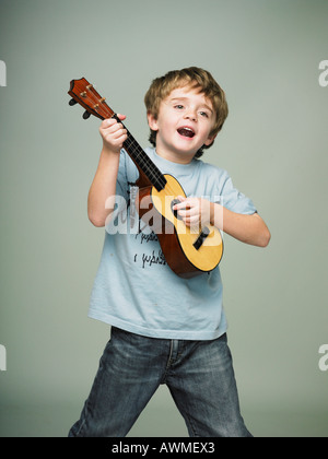 Garçon faisant semblant d'être une rock star avec petite guitare de childs Banque D'Images