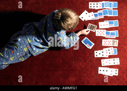 Garçon fixant et cartes à jouer par lui-même Banque D'Images