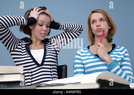 Agacé tandis que deux filles faire leurs devoirs ensemble Banque D'Images