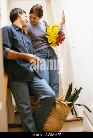 Couple leaning against wall, woman holding bouquet Banque D'Images