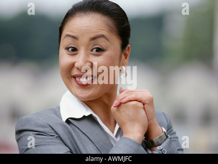 Businesswoman smiling, mains ensemble, portrait Banque D'Images