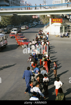 La Chine, la Province du Xinjiang, Urumqi, groupe d'enfants crossing street Banque D'Images