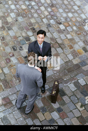 Deux hommes d'échanger des cartes, elevated view Banque D'Images