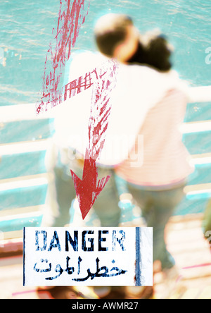 Couple standing par rail avec flèche rouge, texte arabe et "danger" du texte, montage, close-up Banque D'Images