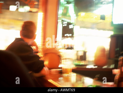 Les gens assis à table dans un restaurant, un éclairage en arrière-plan, floue. Banque D'Images