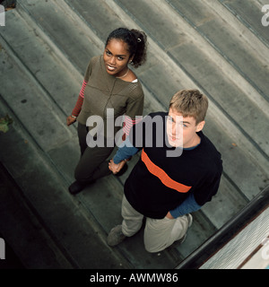 Jeune couple en bas de marche, à la recherche jusqu'à l'appareil photo, high angle view Banque D'Images