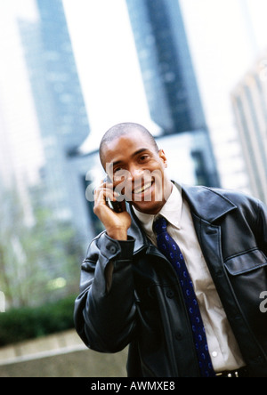 Businessman using cellular phone, en face de l'édifice, catégorie gratte-ciel, portrait. Banque D'Images