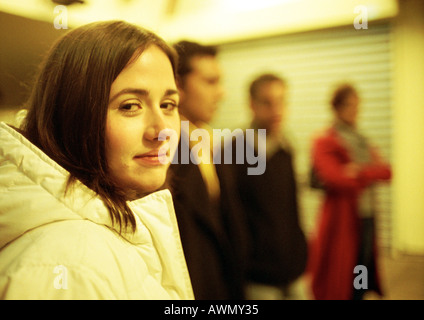 Young woman looking at camera, jeunes gens debout en arrière-plan Banque D'Images