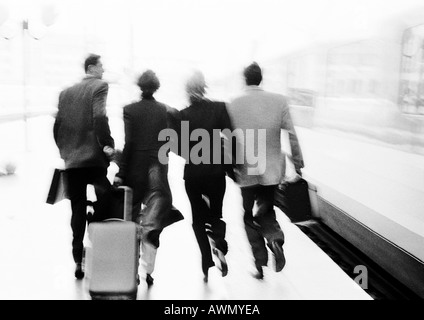 Groupe de gens d'affaires se dépêchant sur plate-forme du train, vue arrière, floue, b&w. Banque D'Images